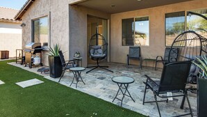 A patio area with a grill, chairs, and a hanging chair. - 5 Mi to Estrella Mtn Park! Home w/ Outdoor Oasis (Goodyear)