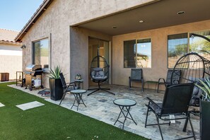 A patio area with a grill, chairs, and a hanging chair. - 5 Mi to Estrella Mtn Park! Home w/ Outdoor Oasis (Goodyear)