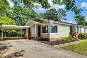 A single-story mobile home with a covered porch, a brick foundation, and a small front yard. - 5 Mi to Dtwn Greenville! Getaway w/ Deck & Yard (Greenville)