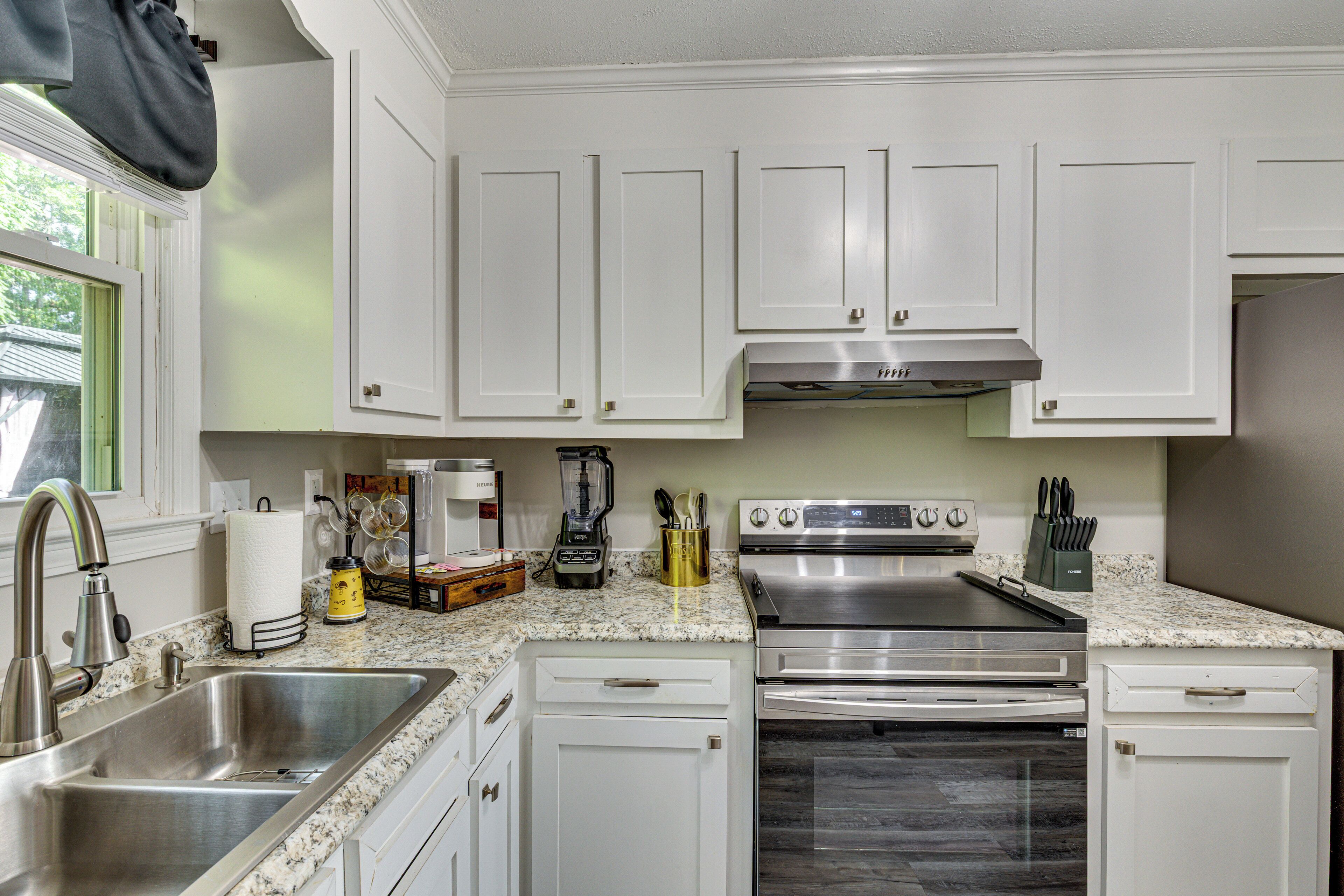 A modern kitchen with white cabinets, stainless steel appliances, and a granite countertop.