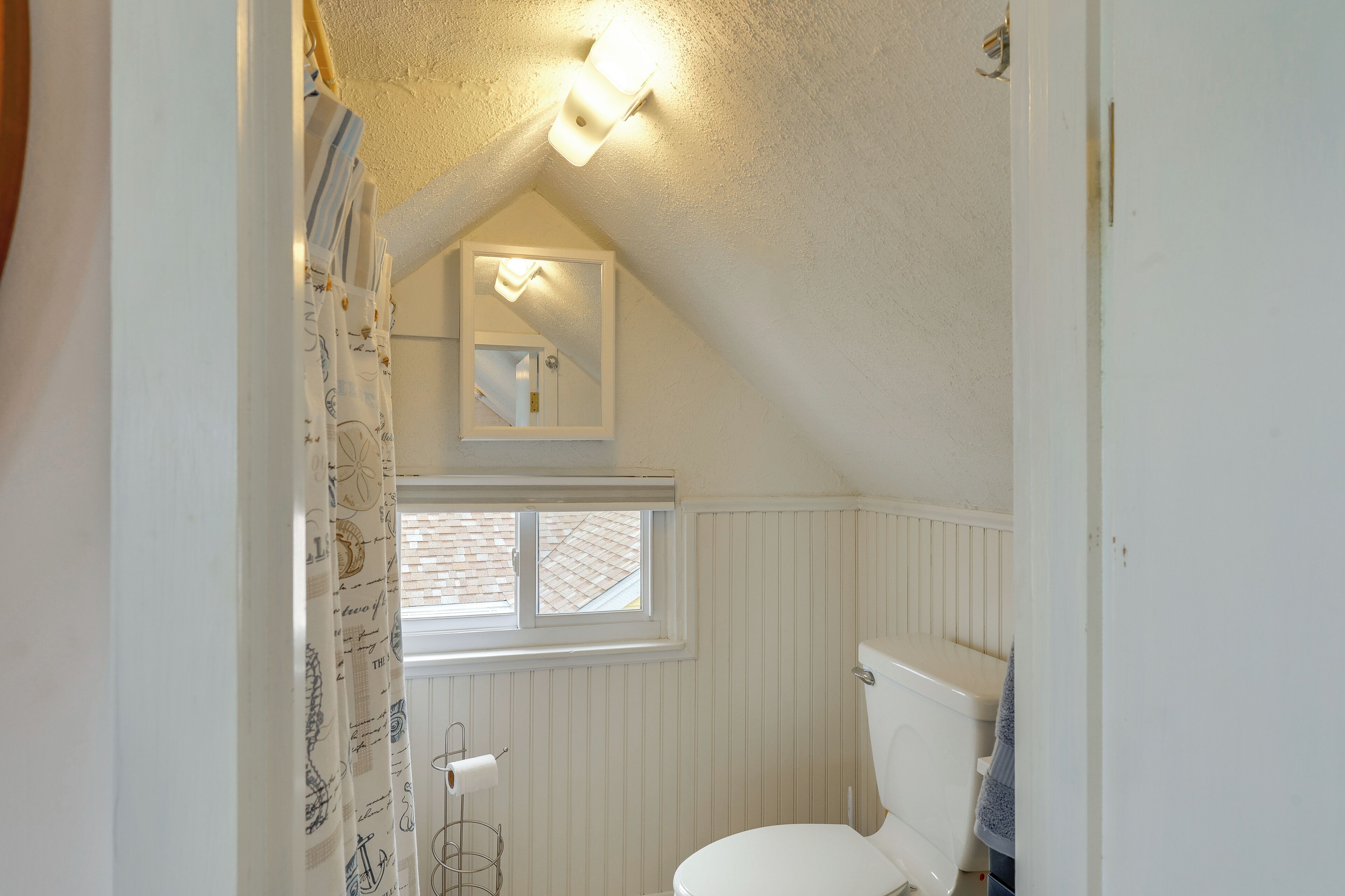 Une petite salle de bain blanche, avec une fenêtre, des toilettes et un porte-serviettes.