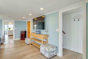 Una habitación con un banco de madera, una mesita y un espejo.