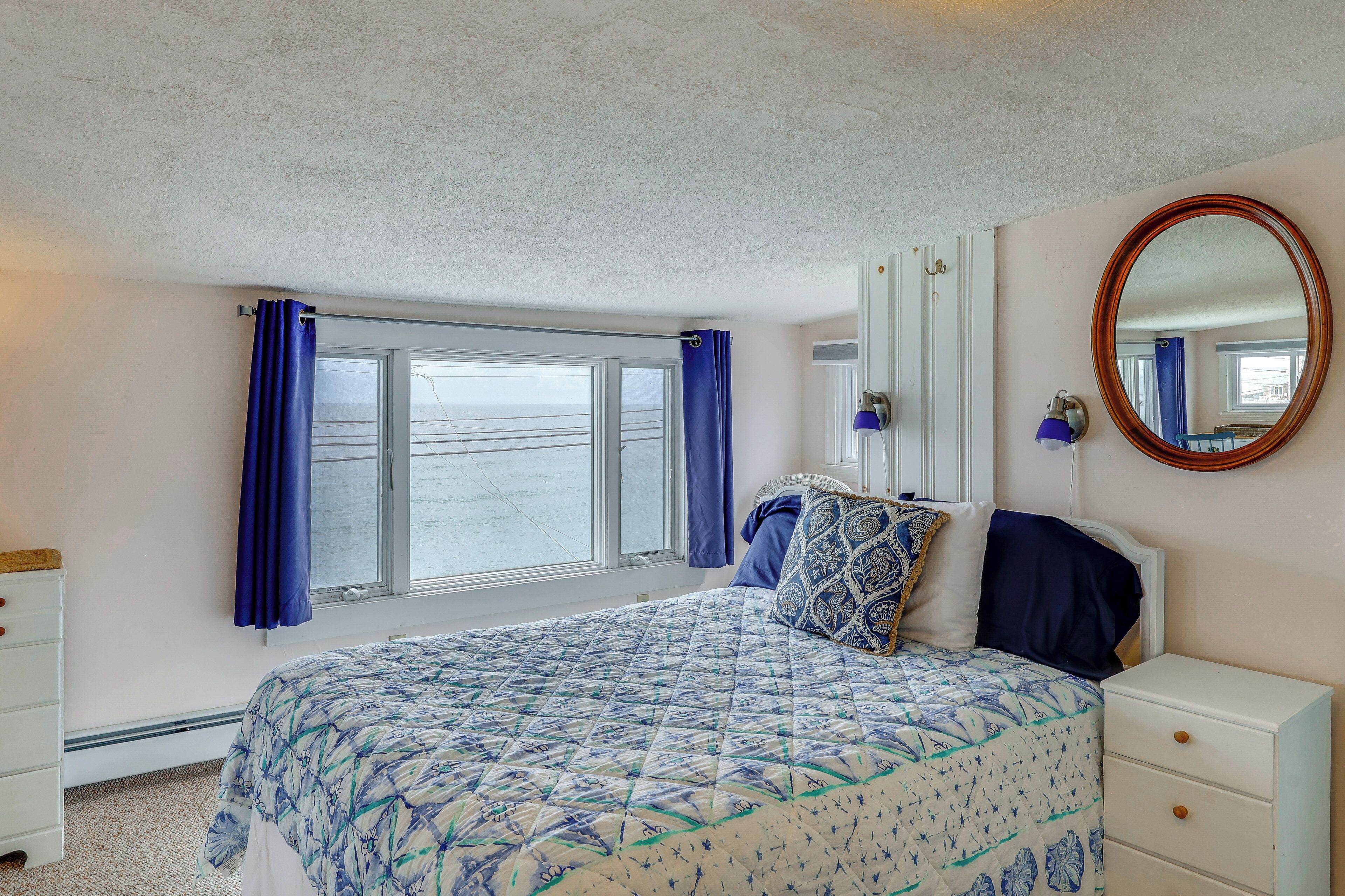 Un dormitorio con cama, cómoda, espejo y ventana con cortinas.