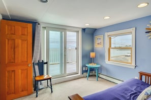 Una habitación con cama, una silla, una mesa, un ventanal y una puerta.