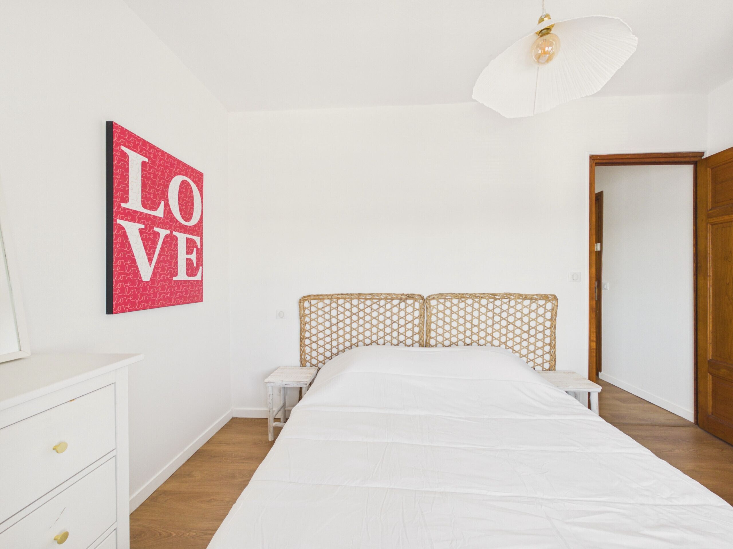 Ein Schlafzimmer mit Bett, Nachttisch, Kommode und Tür.
