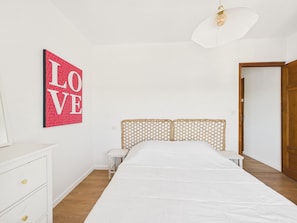 A bedroom with a bed, a nightstand, a dresser, and a door. - Apartment for 4 - Shared Garden - Terrace - WiFi (Fouesnant)