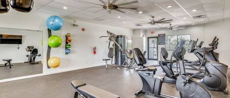 A gym with exercise equipment, a bench, and a ceiling fan.