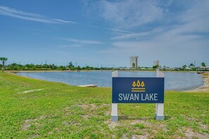 Schild für Schwanensee mit Blick auf einen See und Gebäuden im Hintergrund.