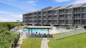 A multi-story hotel with a swimming pool surrounded by a white fence. - Dunescape 132-Ocean Front Condo w/Pool (Atlantic Beach)