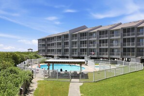 A multi-story hotel with a swimming pool surrounded by a white fence. - Dunescape 132-Ocean Front Condo w/Pool (Atlantic Beach)