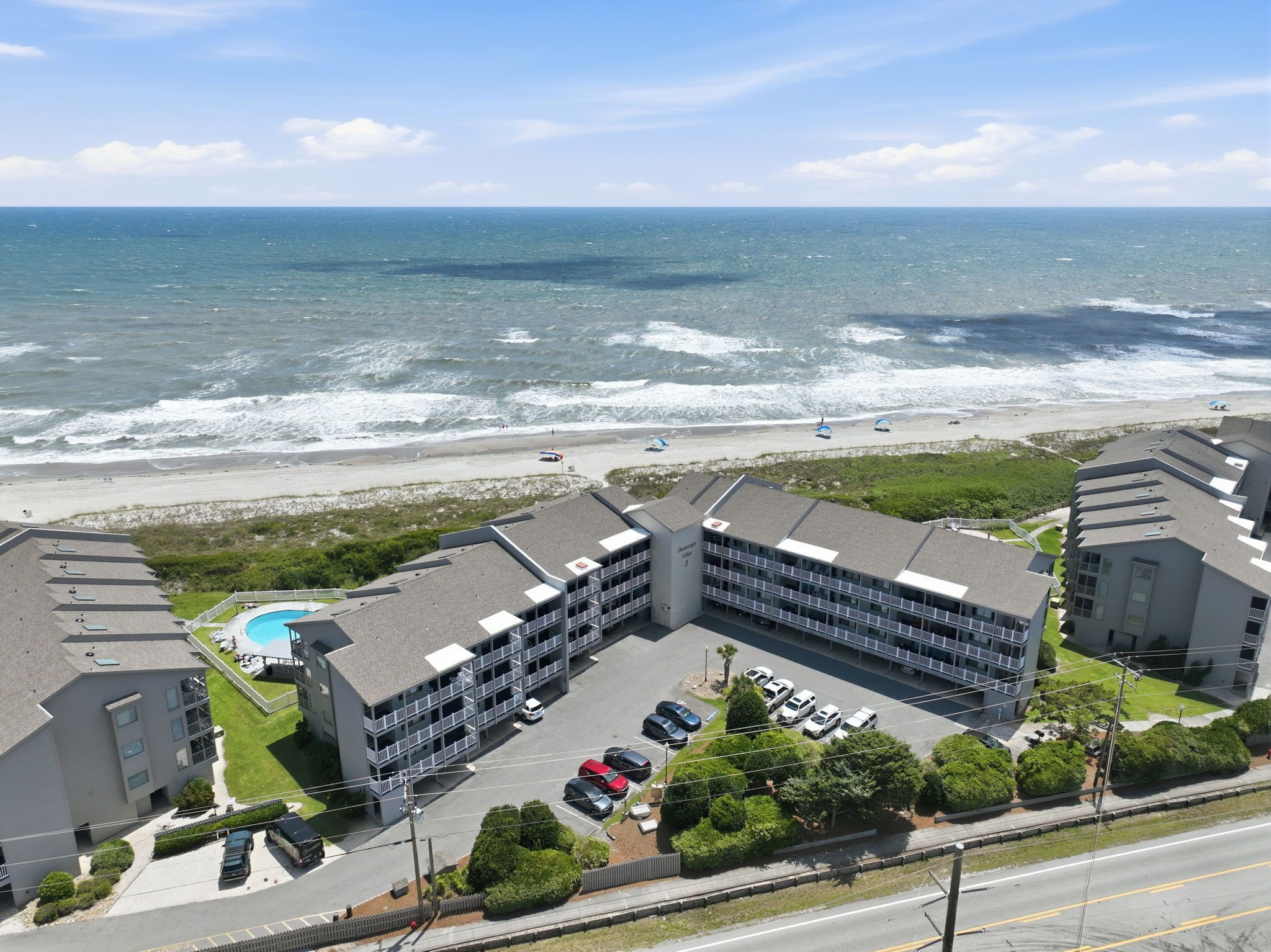 A hotel with a pool, parking, and ocean views.