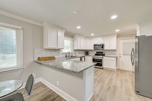 Eine moderne Küche mit weißen Schränken, Granit-Arbeitsplatten, Edelstahlgeräten und einem Glastisch.