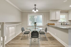 A dining area with a glass-top table and four chairs, a ceiling light fixture, and a window with blinds. - Lake Norman Launchpad: Home Near Dtwn Mooresville (Mooresville)