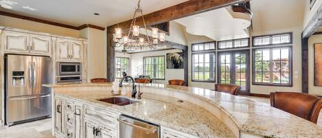 A spacious kitchen with a large island, stainless steel appliances, and a farmhouse-style ceiling.