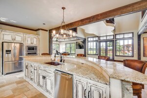 A spacious kitchen with a large island, stainless steel appliances, and a farmhouse-style ceiling.
