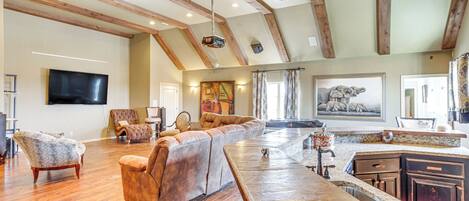 A spacious living area with a long wooden bench, a leather sofa, and a television mounted on the wall.