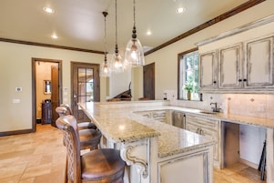 A spacious kitchen with a large island, bar stools, and pendant lighting.