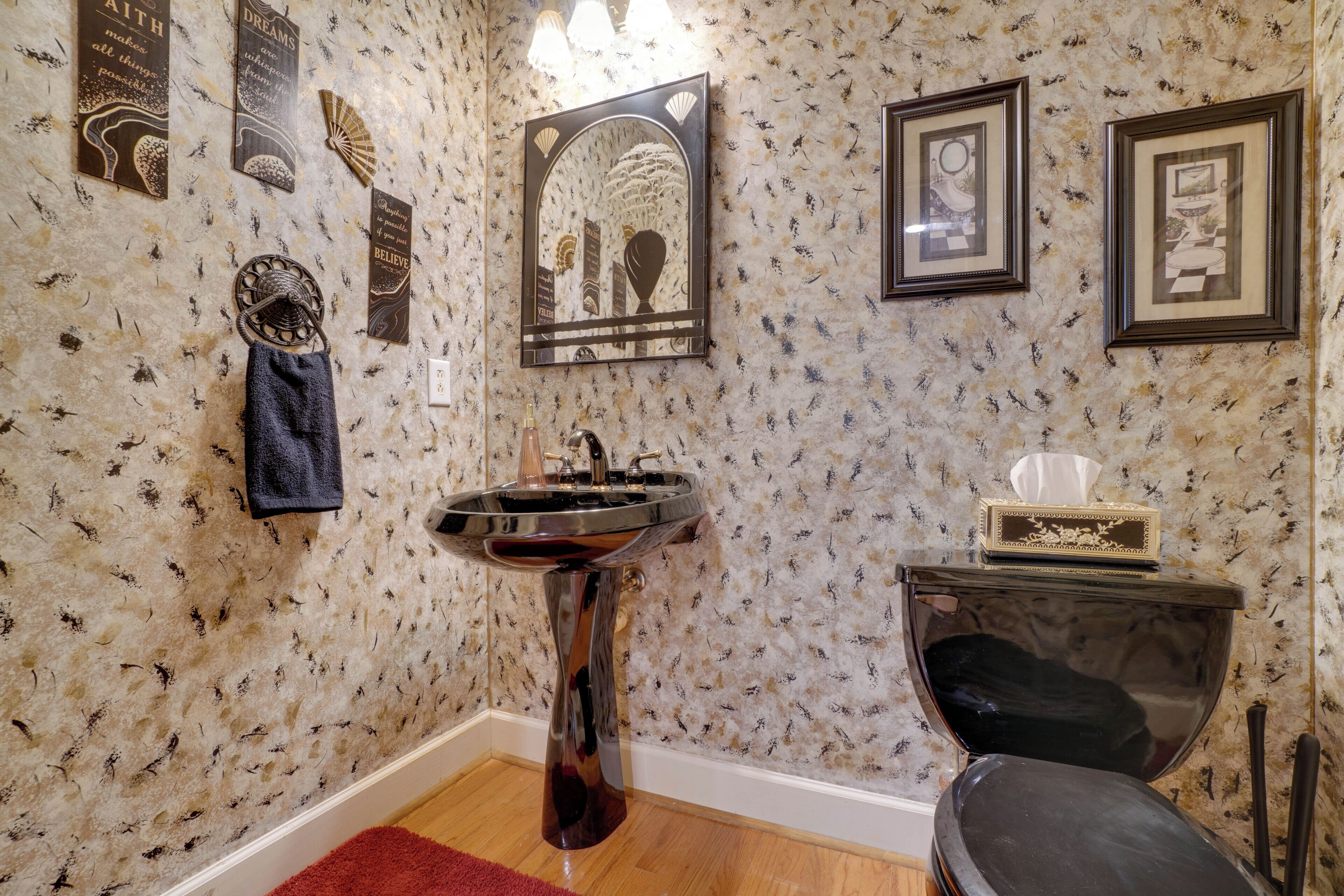 Ein Badezimmer mit Marmorwand, Waschbecken, Handtuchhalter und gerahmten Bildern.