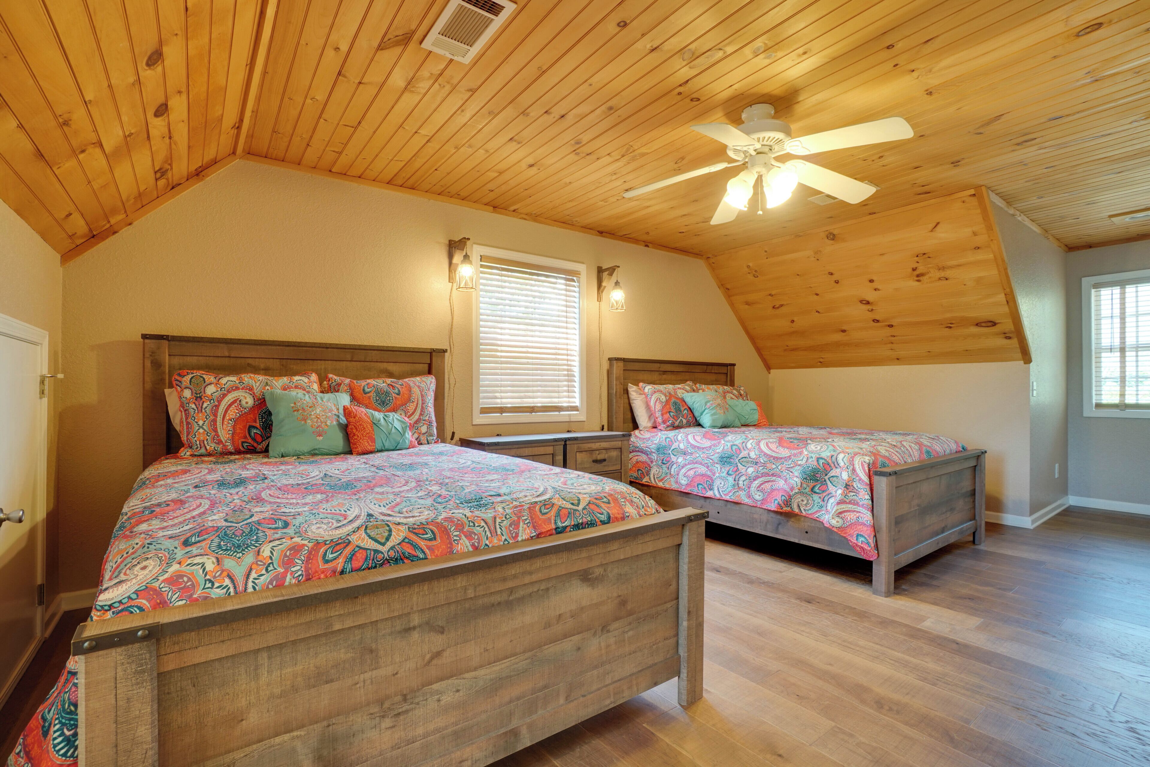 A bedroom with two wooden beds, a sloped ceiling, and a ceiling fan.