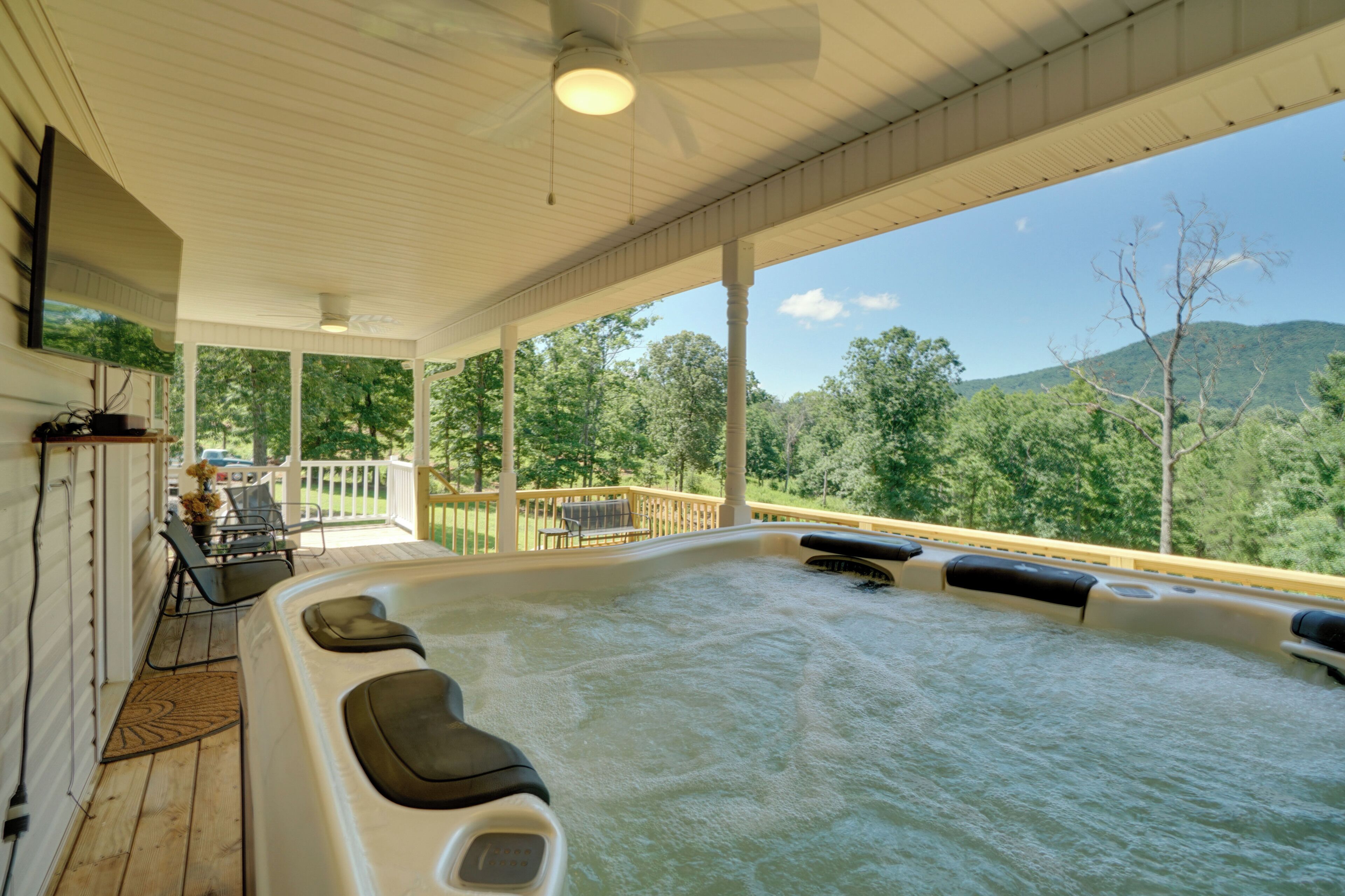 Ein Whirlpool mit Holzterrasse und Blick auf einen bewaldeten Berg.