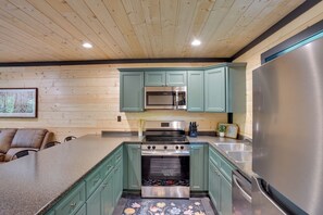 A kitchen with wooden walls, a stainless steel refrigerator, a microwave, an oven, and a sink. - Kentucky Lake Access! 2-unit Combo w/ Decks (Murray)