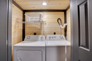 A laundry area with two white front-loading washing machines, a drying rack, and a hose. - Kentucky Lake Access! 2-unit Combo w/ Decks (Murray)
