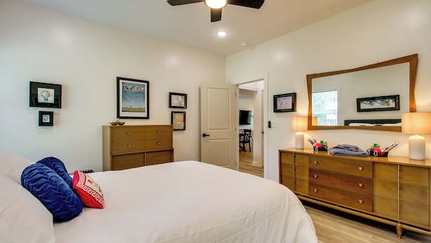 A bedroom with a bed, dresser, and a ceiling fan. - 'the Romano Retreat' Modern Lake Guntersville Home (Scottsboro)