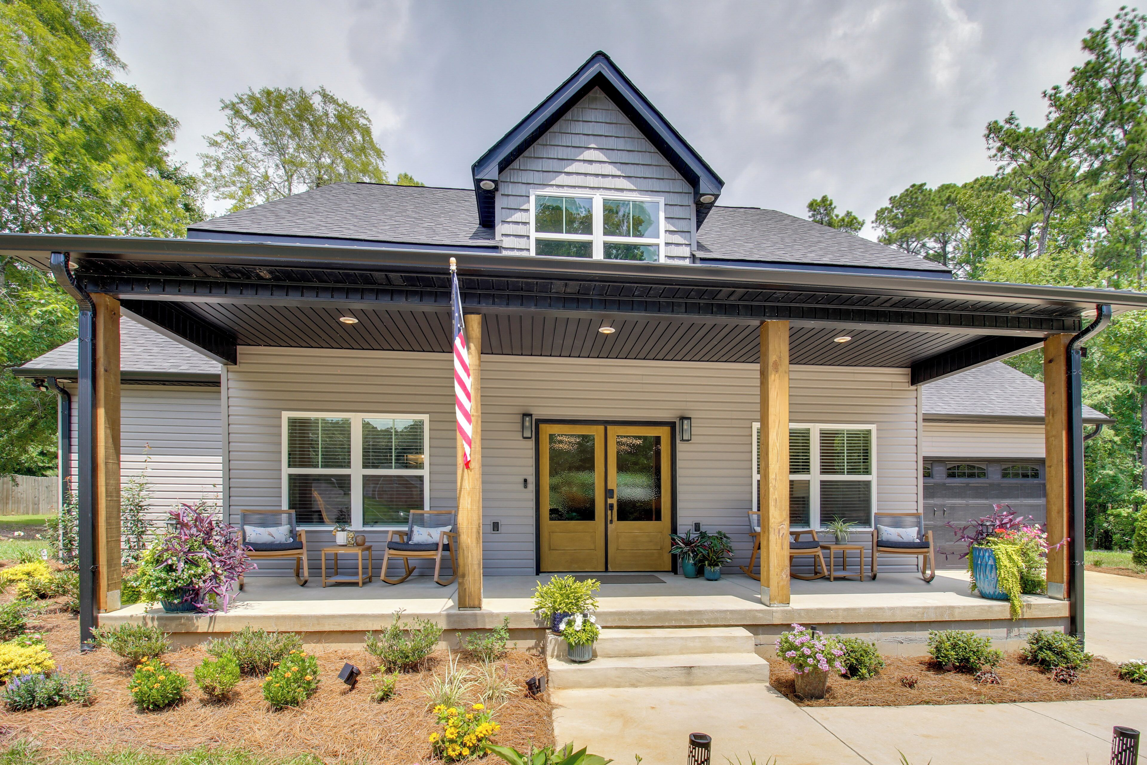 A two-story house with a covered porch, a front door, and a flagpole.