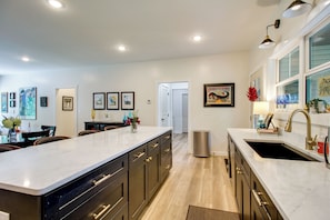 A modern kitchen with a central island, built-in appliances, and a dining area with chairs. - 'the Romano Retreat' Modern Lake Guntersville Home (Scottsboro)