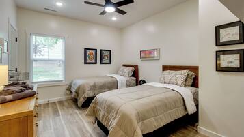 A bedroom with two beds, a ceiling fan, and a window with blinds.