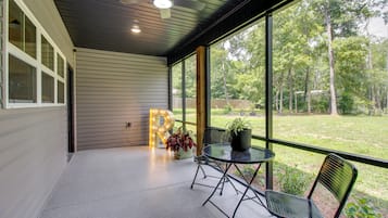 A covered patio with a table and chairs, a large illuminated 'R' sign, and a view of a wooded area.