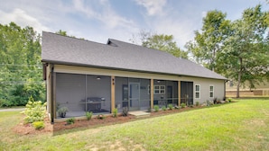 A single-story house with a large sliding glass door, a covered patio, and a well-maintained lawn. - 'the Romano Retreat' Modern Lake Guntersville Home (Scottsboro)