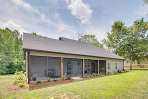 A single-story house with a large sliding glass door, a covered patio, and a well-maintained lawn. - 'the Romano Retreat' Modern Lake Guntersville Home (Scottsboro)