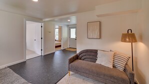 Una sala moderna con un sofá, una lámpara y un pasillo que conduce a otra habitación.