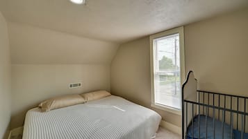 A bedroom with a bed, a window, and a crib.
