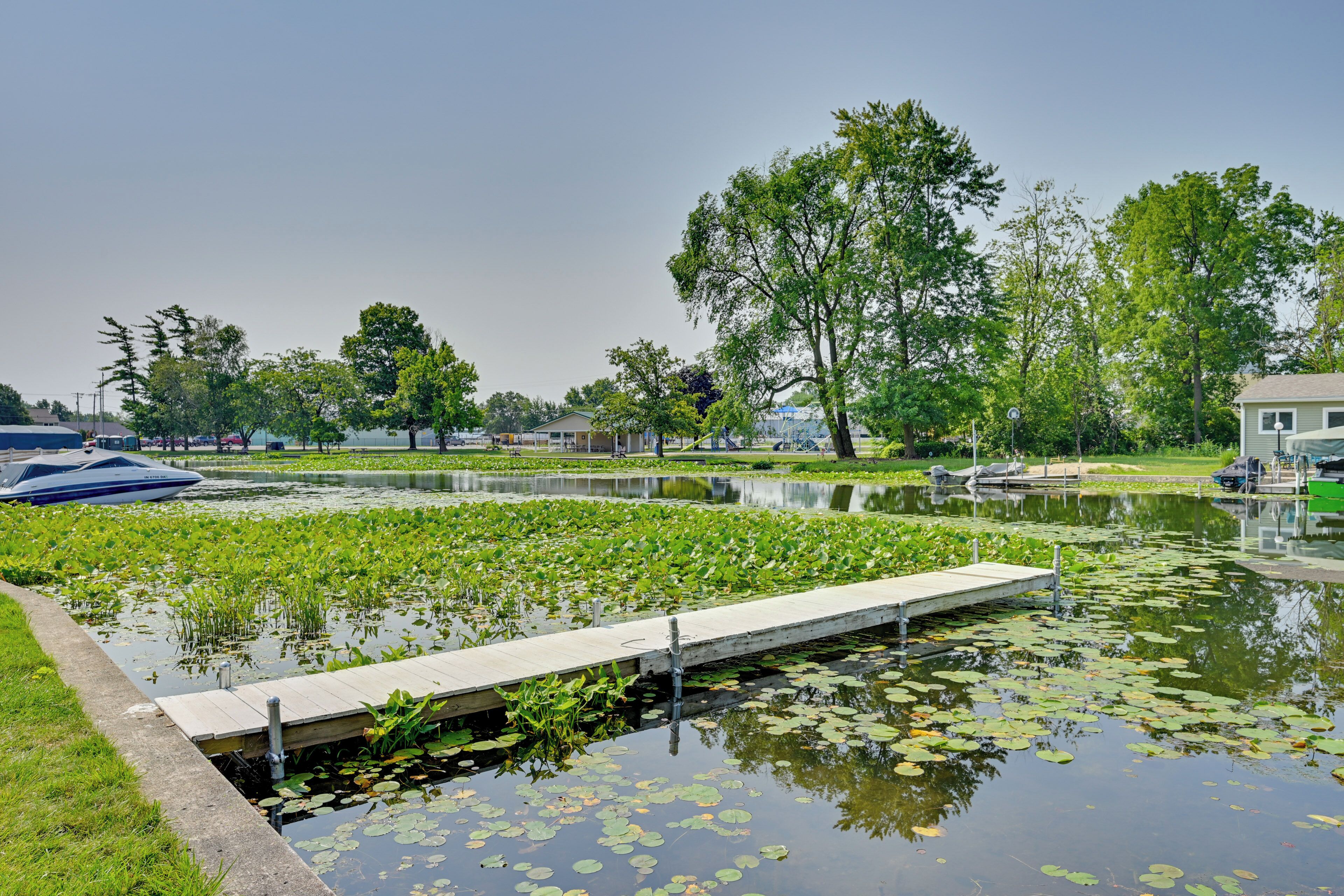 A serene park with a pond, a wooden dock, and a boat.