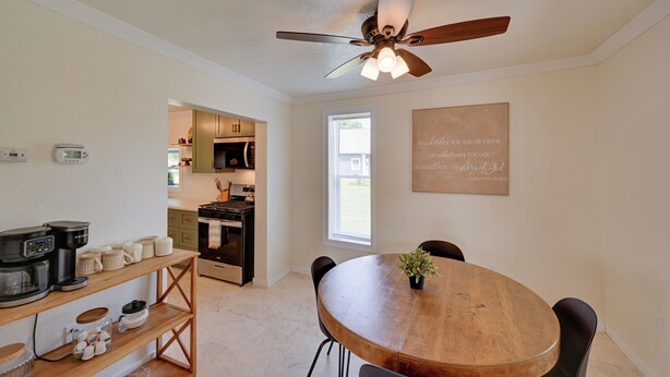 Una cocina moderna con comedor, ventilador de techo y una frase motivadora en la pared.