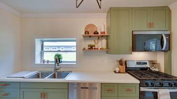 A modern kitchen with green cabinets, a stainless steel dishwasher, a built-in oven, and a microwave.