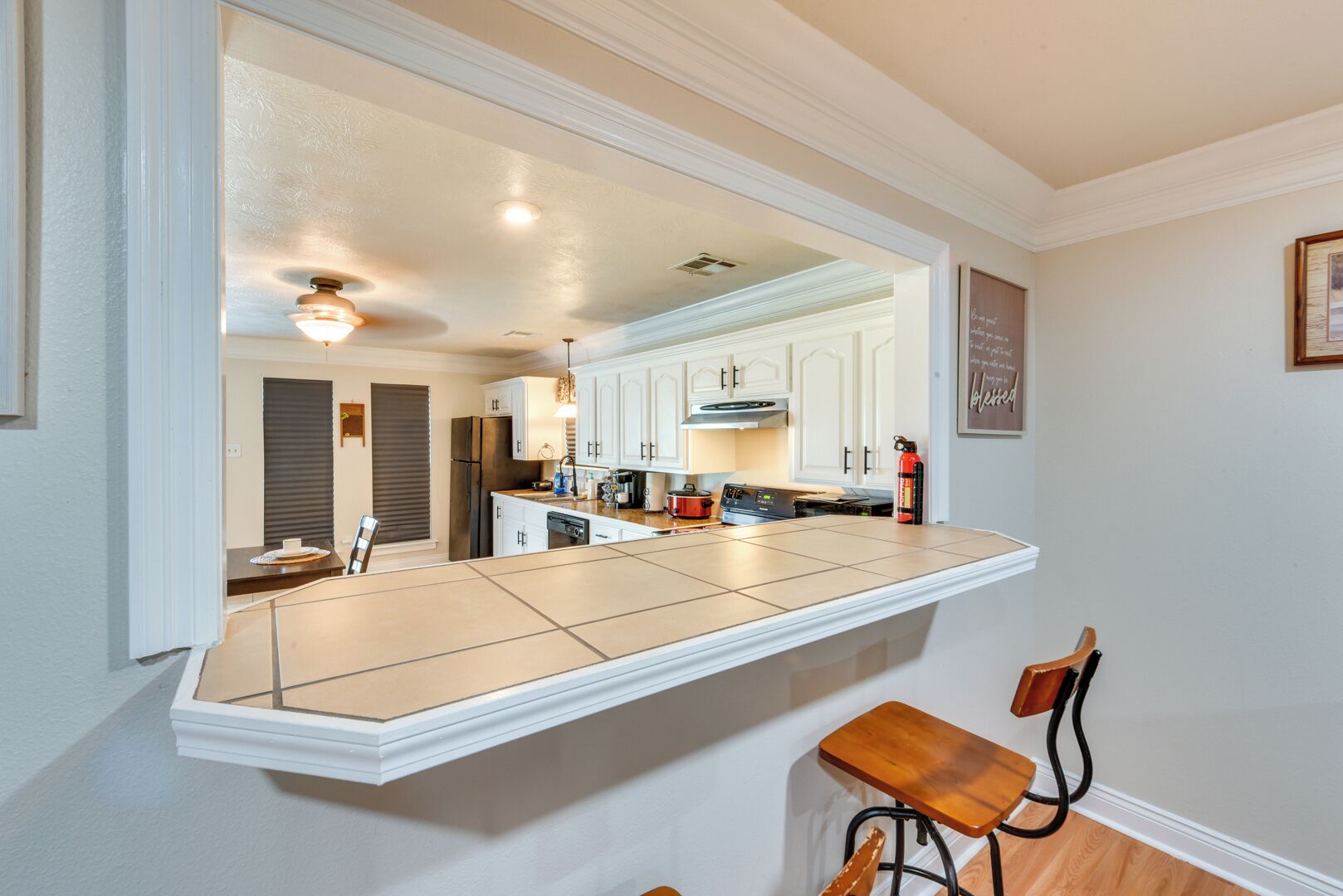 A modern kitchen with white cabinetry, a large island, and a bar stool.