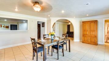 A dining area with a table set for four, surrounded by chairs, and a ceiling fan overhead.