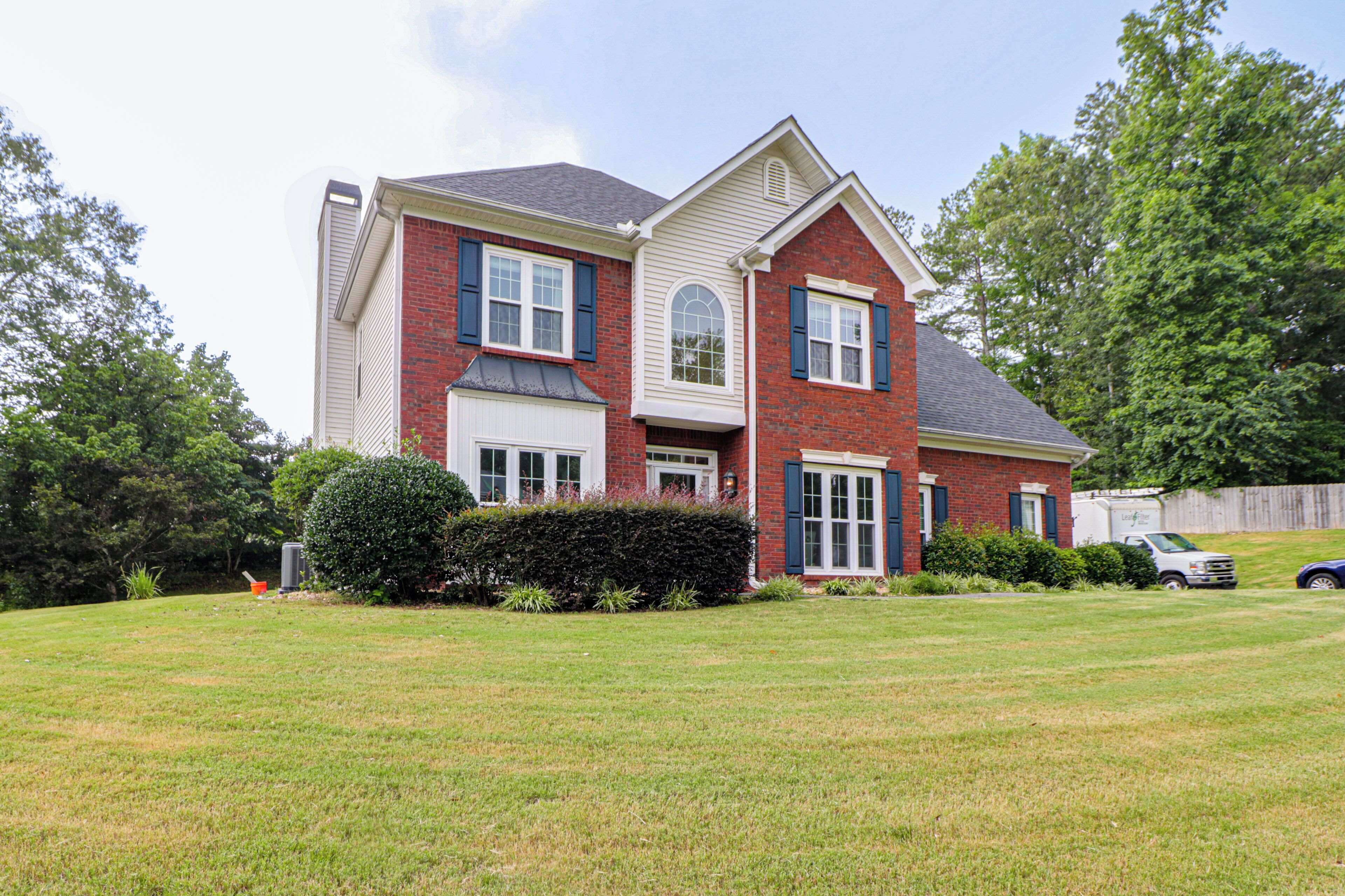 A two-story house with a large front lawn, a garage, and a driveway.