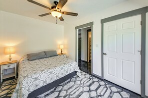 A bedroom with a bed, nightstands, a ceiling fan, a door, and a patterned rug. - Bring Your Boat! Updated Cabin in Priest River (Priest River)