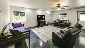 A modern living room with a sofa, armchairs, a coffee table, and a TV. - Bring Your Boat! Updated Cabin in Priest River (Priest River)
