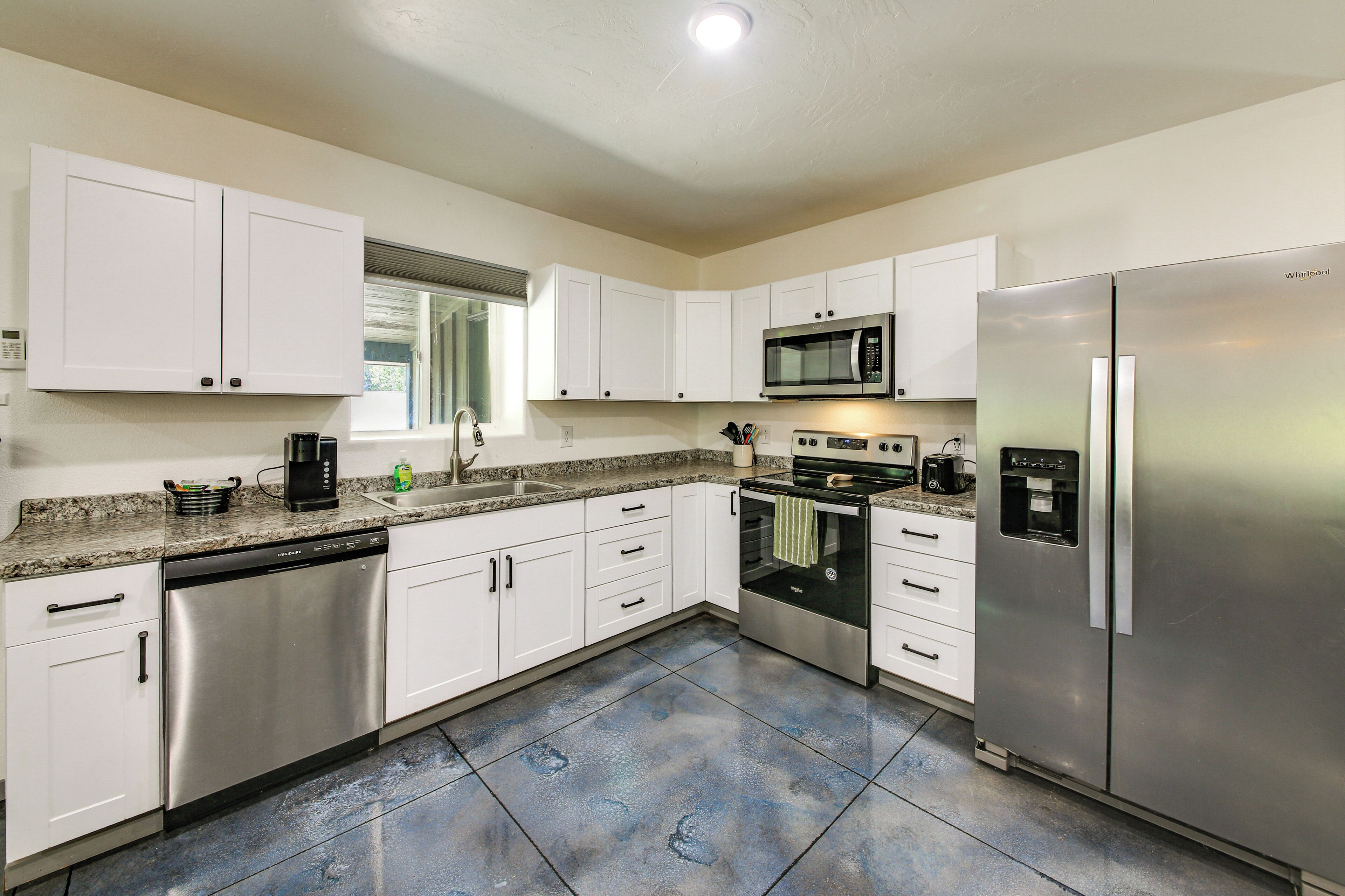 A modern kitchen with white cabinets, stainless steel appliances, and a granite countertop.