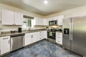 A modern kitchen with white cabinets, stainless steel appliances, and a granite countertop. - Bring Your Boat! Updated Cabin in Priest River (Priest River)