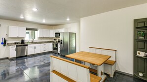 Een moderne keuken met witte kastjes, een roestvrijstalen koelkast en een houten eettafel.