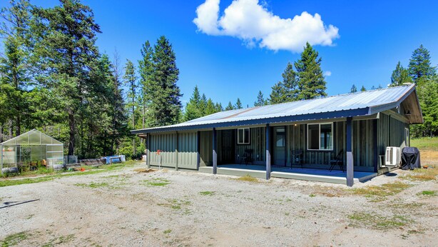 A single-story building with a metal roof, a porch with a bench, and a small shed to the left. - Bring Your Boat! Updated Cabin in Priest River (Priest River)