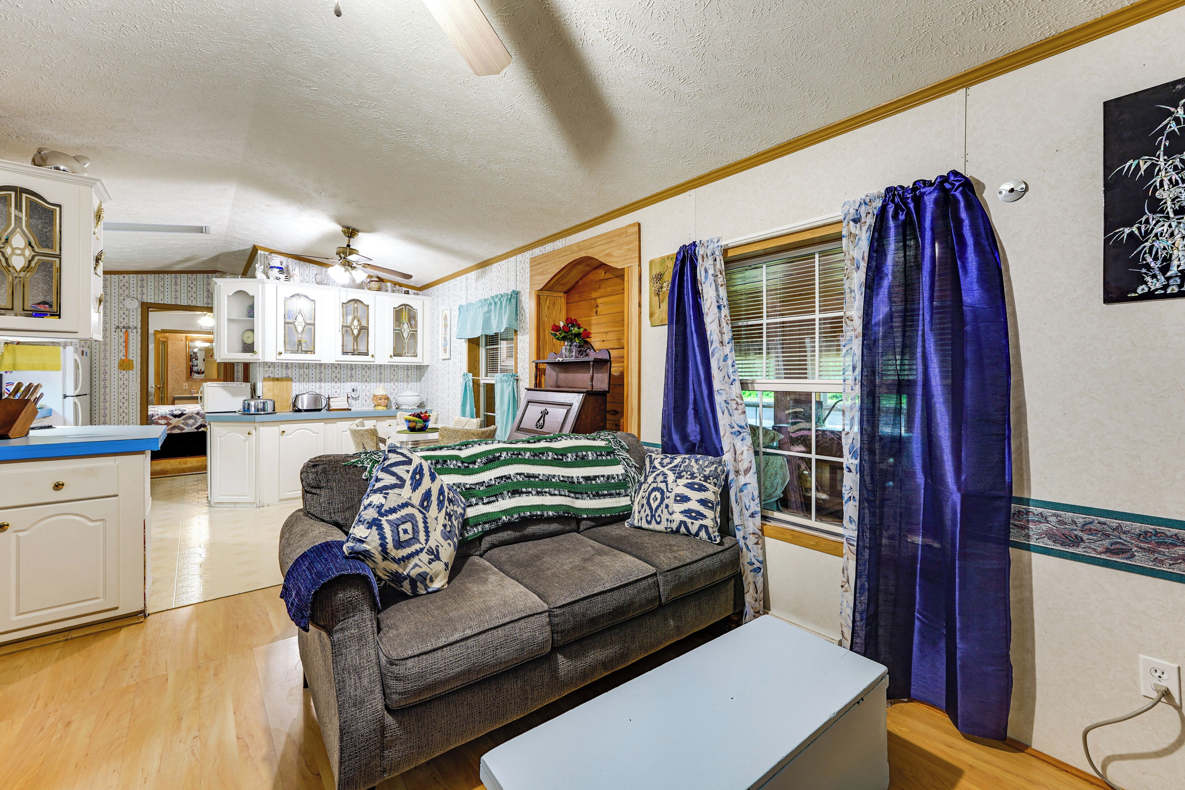 A cozy living room with a sofa, a coffee table, and a kitchen area in the background.