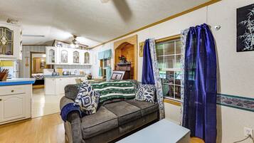 A cozy living room with a sofa, a coffee table, and a kitchen area in the background.