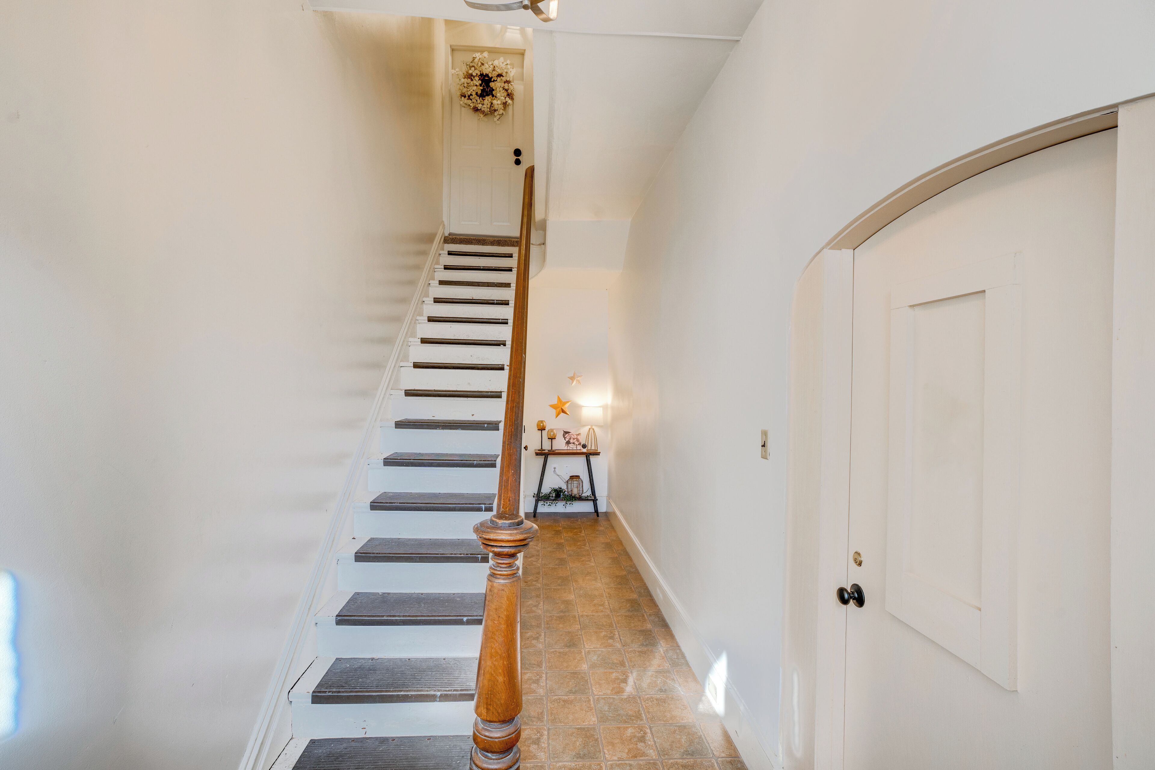 A staircase with a wooden handrail leading to a white door.